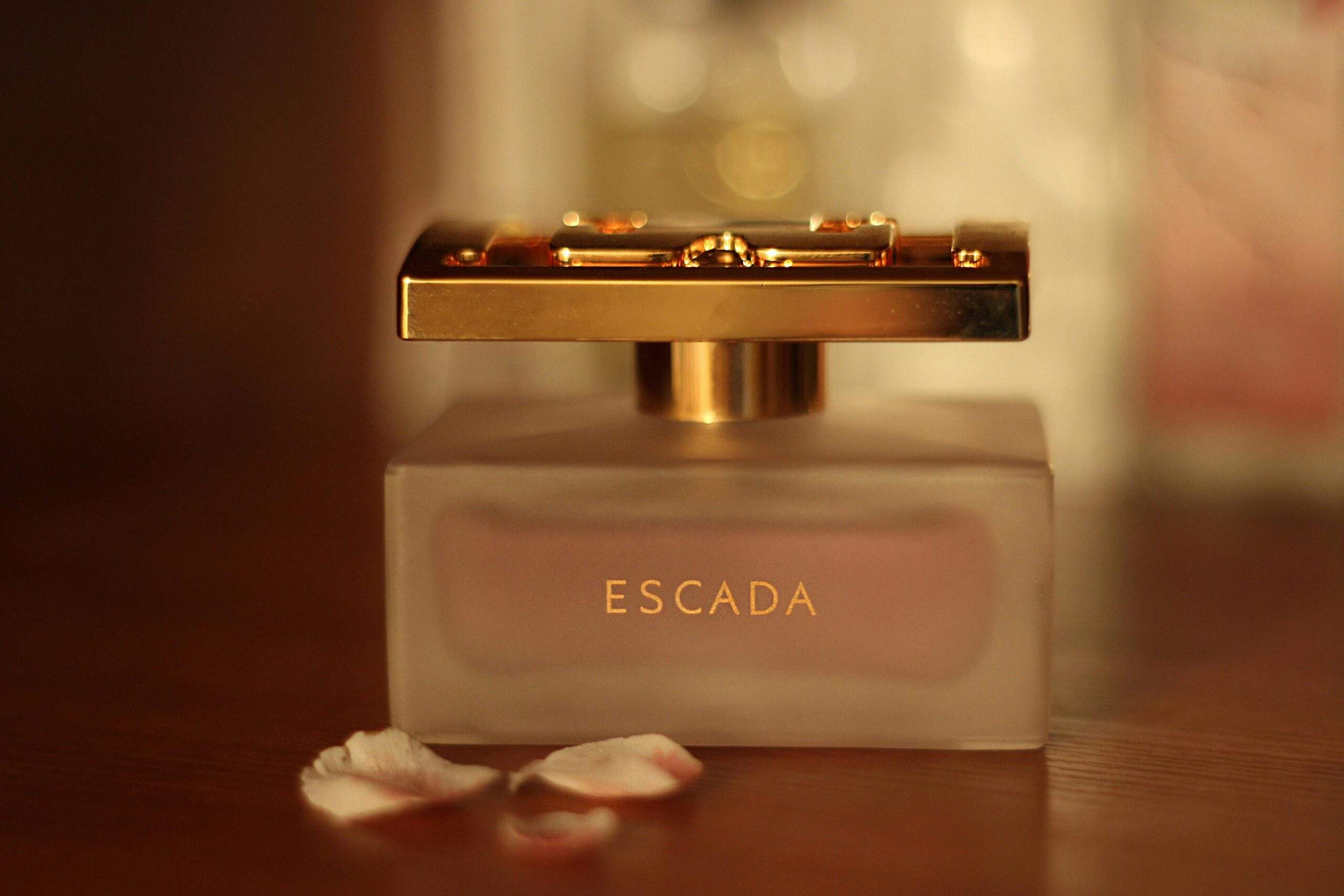 Close-up of a luxury perfume bottle with petals on a wooden table.